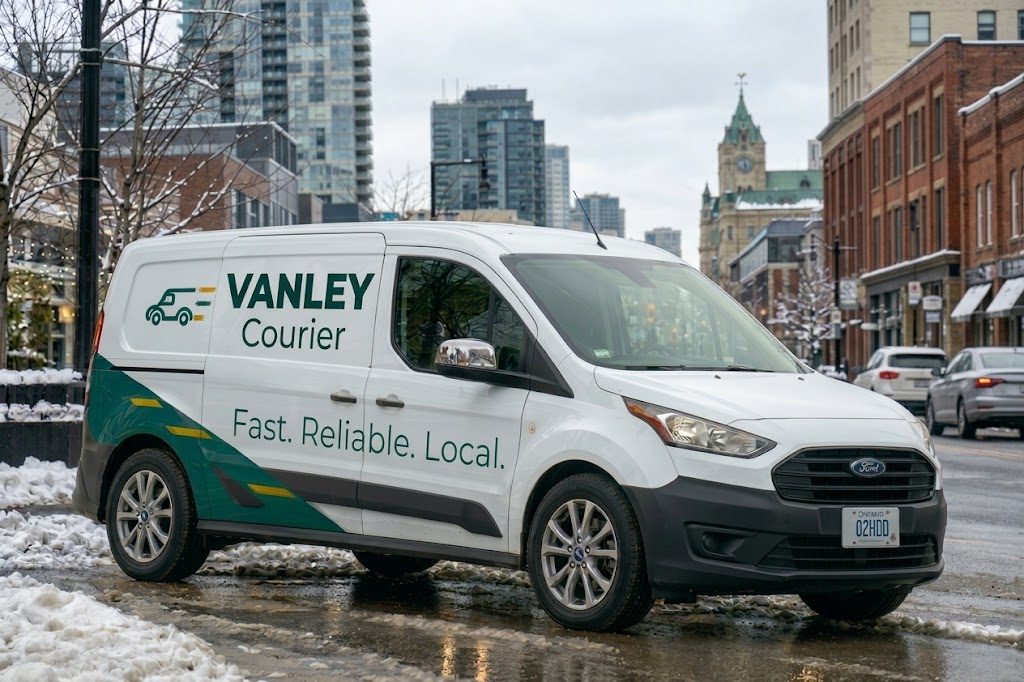 White Vanley Courier cargo van with "Fast. Reliable. Local." on the side, parked on a snowy downtown street